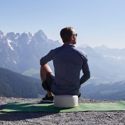 Mann meditiert vor Bergpanorama